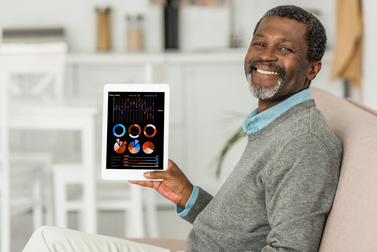 cheerful african american man holding digital tablet with infpographics on screen and smiling at