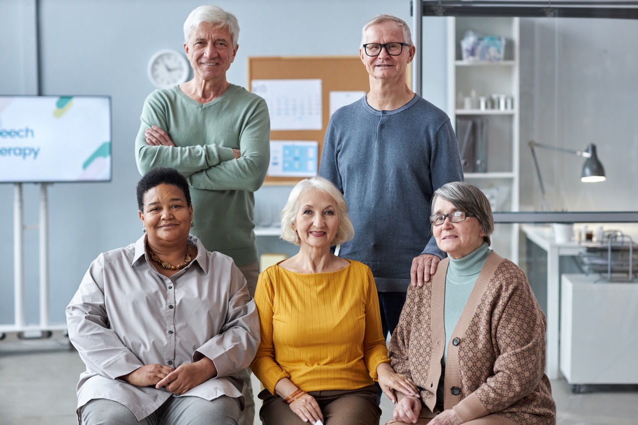 Group multiethnic seniors posing in medical clinic setting all looking at camera